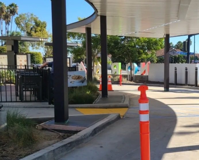 A street with orange cones and a white canopy.